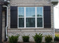 Brick house featuring windows with rustic cedar shutters