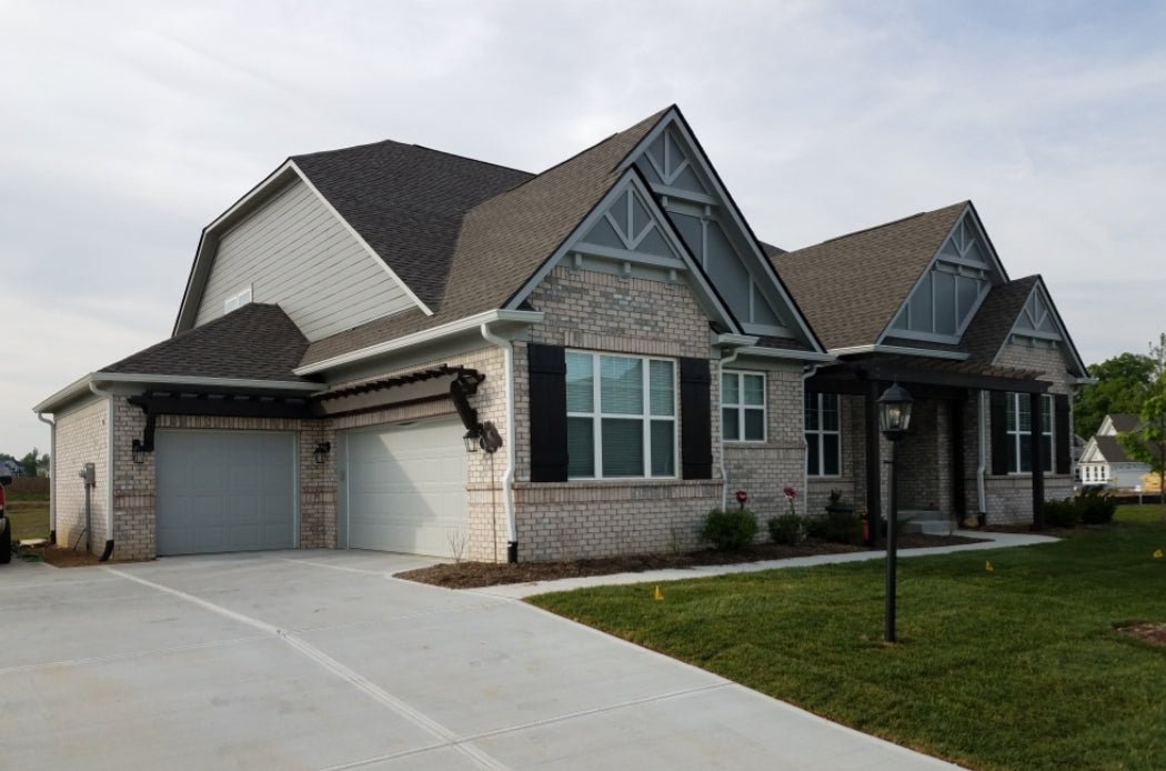 House showcasing rustic cedar shutters with a spacious garage and driveway