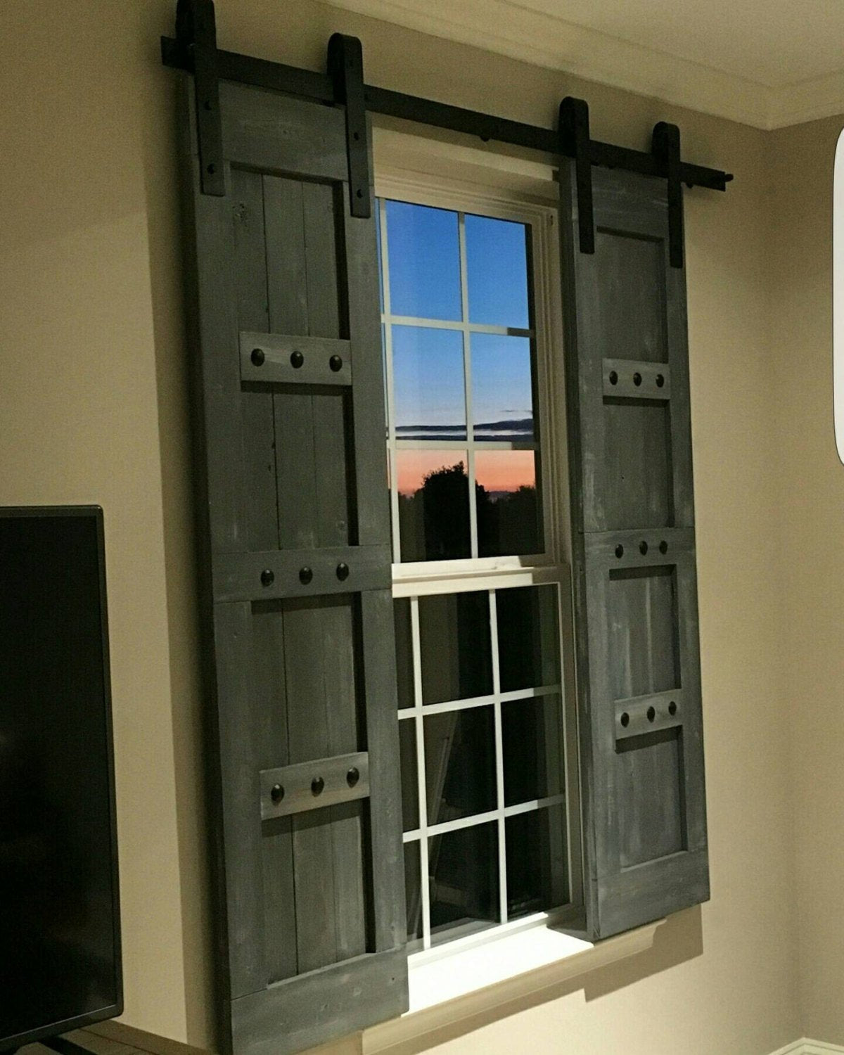 Television room window with a single wooden barn shutter